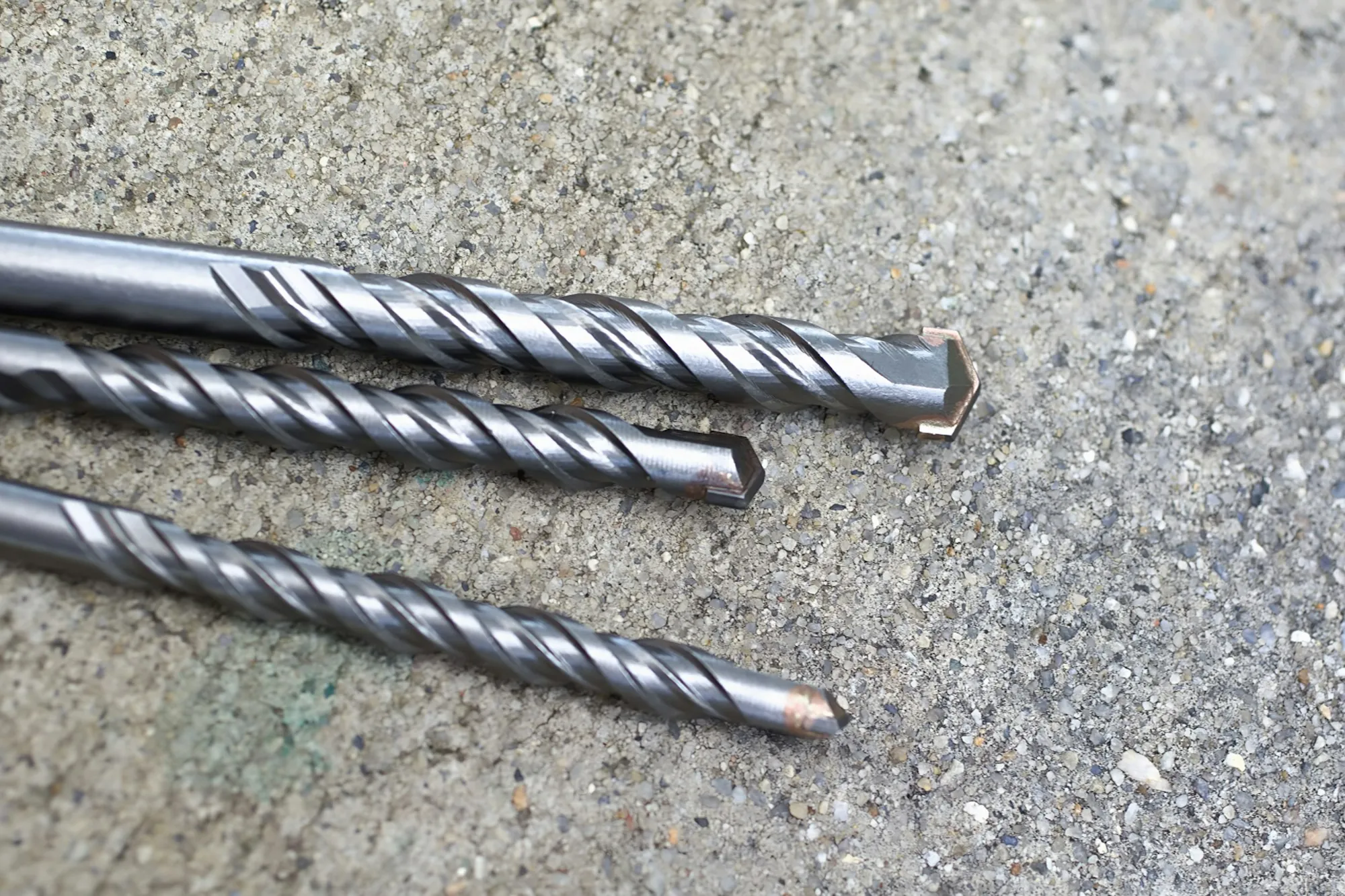 Three masonry drill bits on concrete